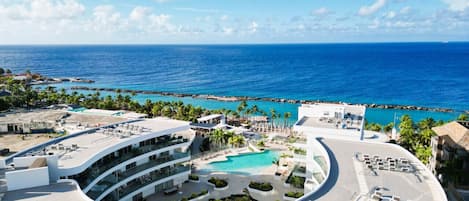 Un resort con piscina central, varios balcones y vista al océano.