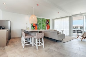 Relax in this spacious living area with a kitchen island, bar stools, and a sofa.