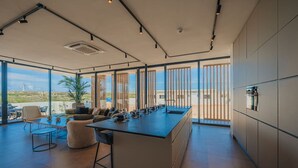A modern kitchen with a large island, large windows, and a view of the landscape.