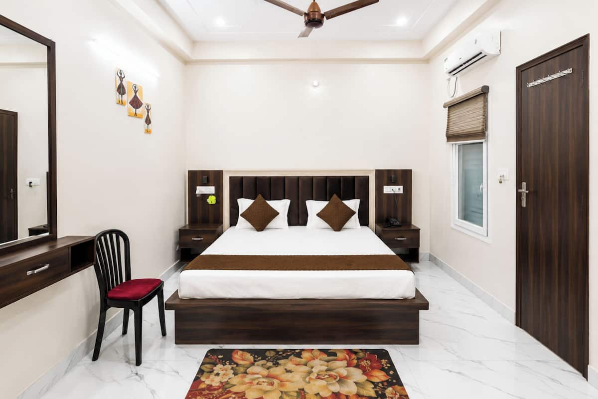 Una habitación de hotel con una cama, mesitas de noche, una silla, un ventilador de techo, una ventana y una puerta.