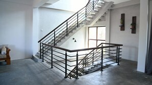 Un interior amplio con una escalera moderna, un banco y un ventanal que proporciona luz natural.