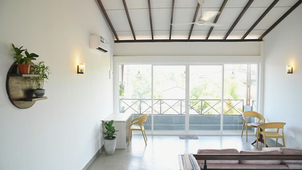Un salón luminoso con un ventanal grande, un ventilador de techo y un sofá.