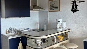 Eine kompakte Küche mit Kochinsel, Barhocker und Kaffeemaschine.