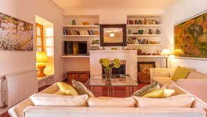 Una sala de estar con un sofá, televisor, estanterías y objetos decorativos.