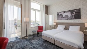 Relax in this stylish room with a large bed, a comfortable chair, and a small table, all set against a vibrant wallpaper backdrop.