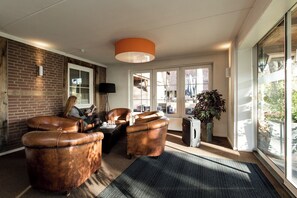 Relax in a cozy living room with a brick accent wall, leather armchairs, and a large window offering a view of the outdoors.
