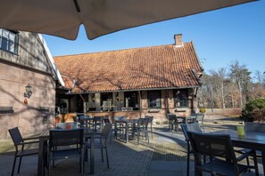 Relax in the shaded outdoor seating area with a brick building backdrop and lush surroundings.