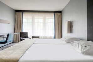 Relax in a spacious room with a large bed, sofa, and desk, offering a comfortable seating area and natural light.