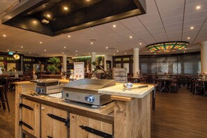 Dine in style at this restaurant with a central island grill, wooden tables, and a bar area.
