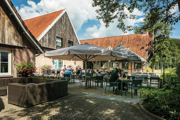 Enjoy al fresco dining in a charming outdoor space with tables, chairs, and lush greenery.