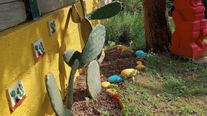 Un jardín de cactus con rocas de colores y una estatua roja.
