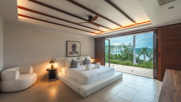 Une chambre moderne avec un grand lit, des tables de chevet et une vue sur des palmiers et une plage.
