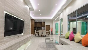 A modern living room with a flat-screen TV, a glass coffee table, and a sofa with colorful cushions. - Luxury Pool Villa A14 3BR/8 Persons (Muang Pattaya)