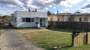 Ett litet hus i ett våningsplan med en veranda, en satellitmottagare och ett trästaket.