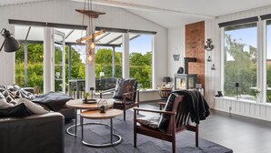 Un salon moderne doté d’une cheminée, de grandes fenêtres et d’un coin salon confortable.