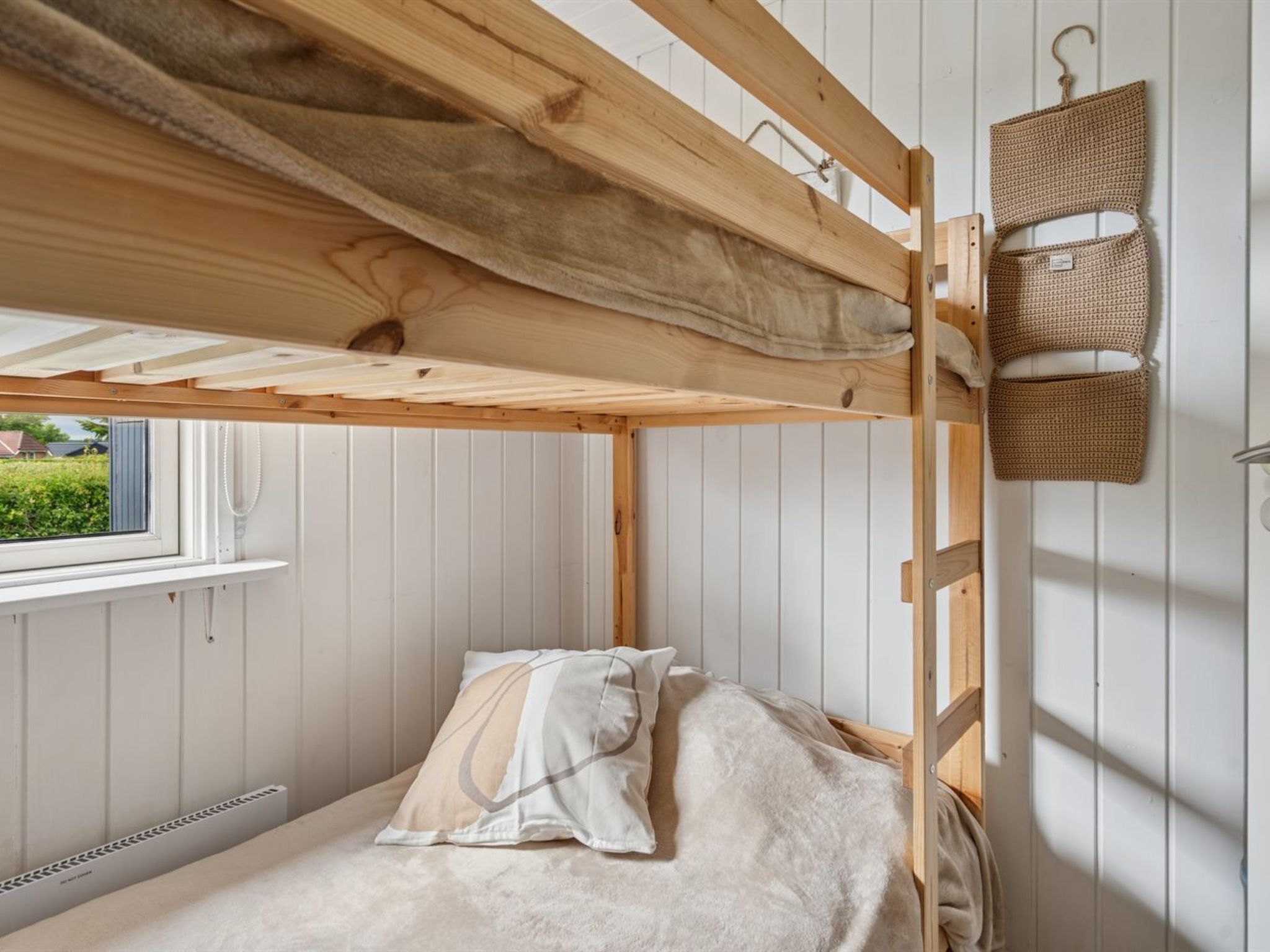 A bunk bed with a window, a hanging light fixture, and a radiator.