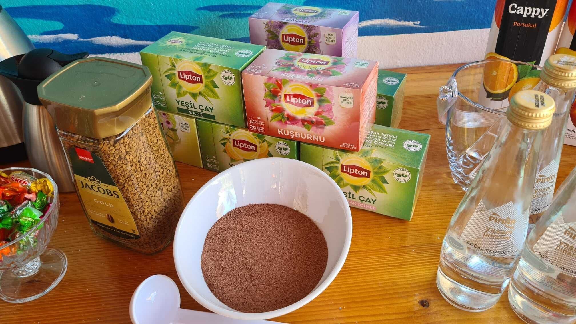 A table with Lipton tea boxes, a jar of spices, a bowl of brown powder, and a glass of water.