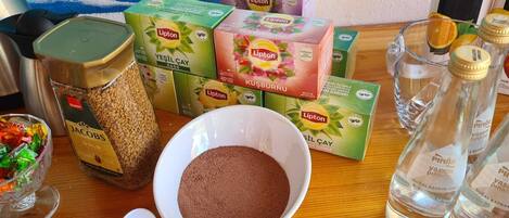 A table with Lipton tea boxes, a jar of spices, a bowl of brown powder, and a glass of water.