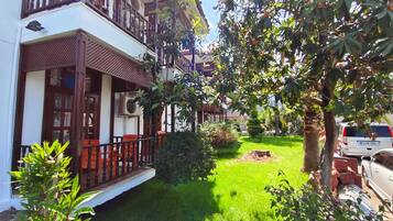 Ein Wohngebäude mit Balkon, kleinem Garten und einem Parkplatz.