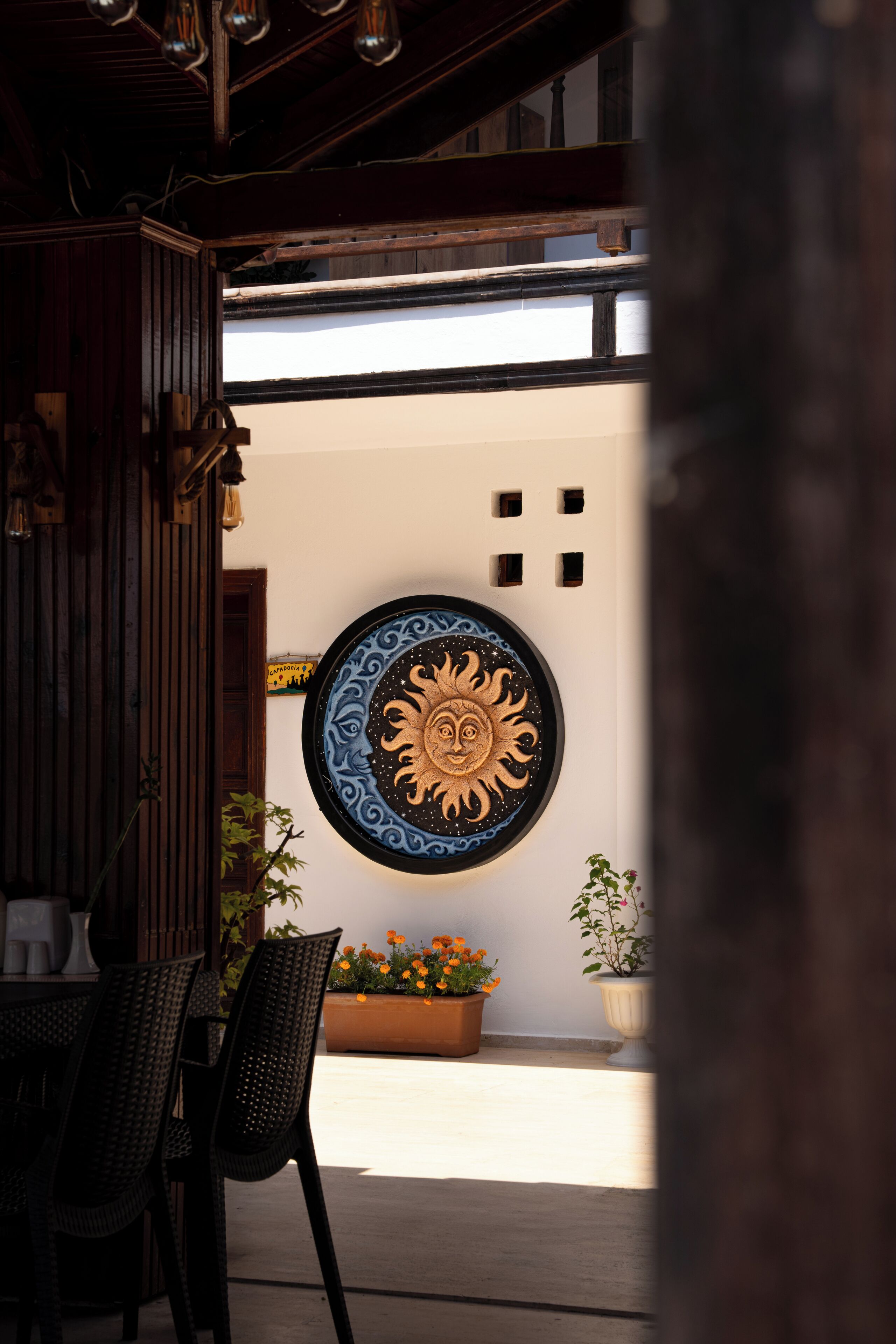 A patio area with a round wall decoration, wooden furniture, and potted plants.