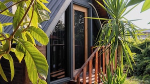 Une cabane en bois avec un toit en pente, une porte en verre et un escalier en bois menant à l’entrée.