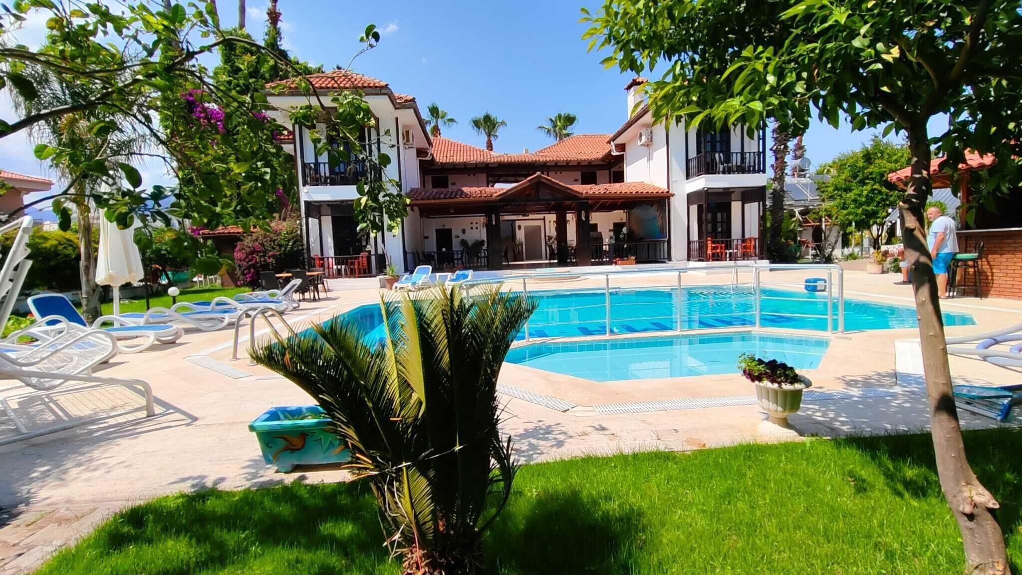 A pool area with lounge chairs and a building with a red-tiled roof.