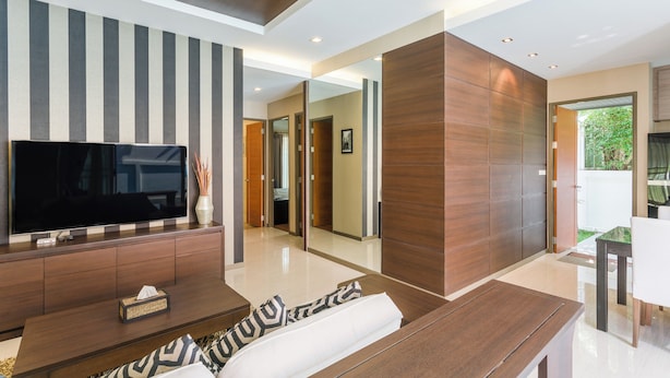 A modern living room with a flat-screen TV, wooden furniture, and a large mirror.
