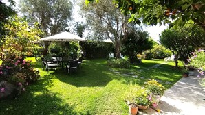 A well-maintained garden with a dining area, outdoor seating, and various potted plants.