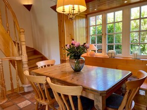 A wooden dining table with chairs, a vase of flowers, and a lamp on a windowsill. - Landhaus Sylt Glück - Holiday home Sylt Glück Morsum, 135sqm for up to 5 people (Sylt-Ost)
