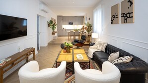 A modern living room with a flat-screen TV, a wooden coffee table, and a black leather sofa. - ChezmoiHomes Realejo Boutique Terrace (Granada)