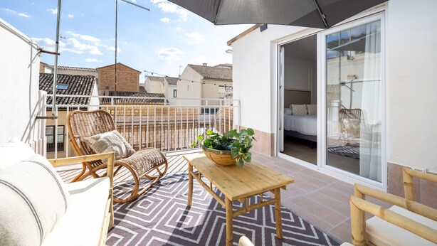 A balcony with wicker furniture, a wooden table, and a potted plant. - ChezmoiHomes Realejo Boutique Terrace (Granada)