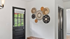 A hallway with a black door, a bench, and wall-mounted woven baskets.