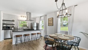 A modern kitchen with a central island, bar stools, and a dining table with placemats.