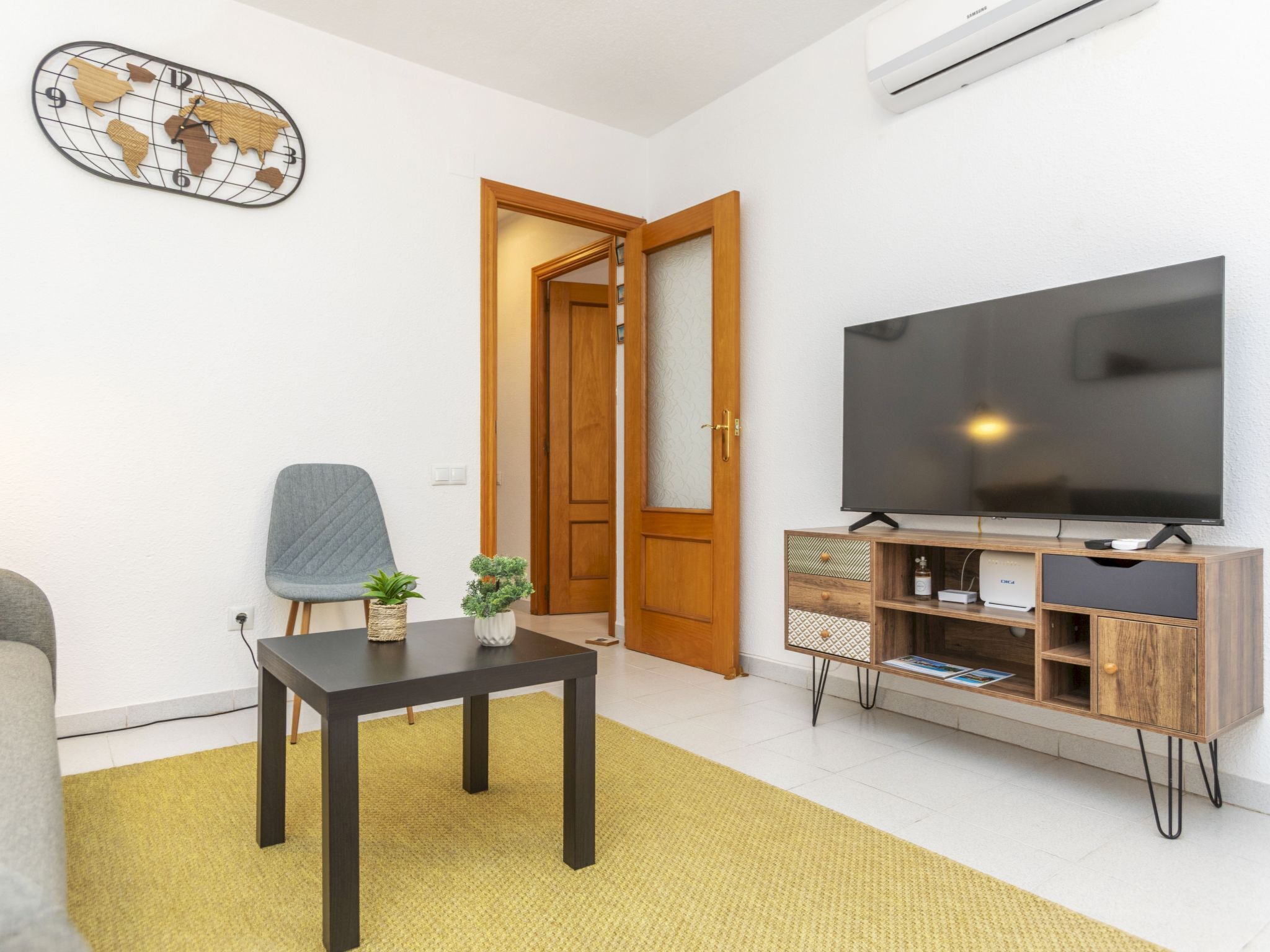 A living room with a TV, a wooden cabinet, a small table, and a chair.