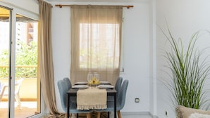 Un comedor con una mesa dispuesta para cuatro, un ventanal corredero y vistas al exterior.