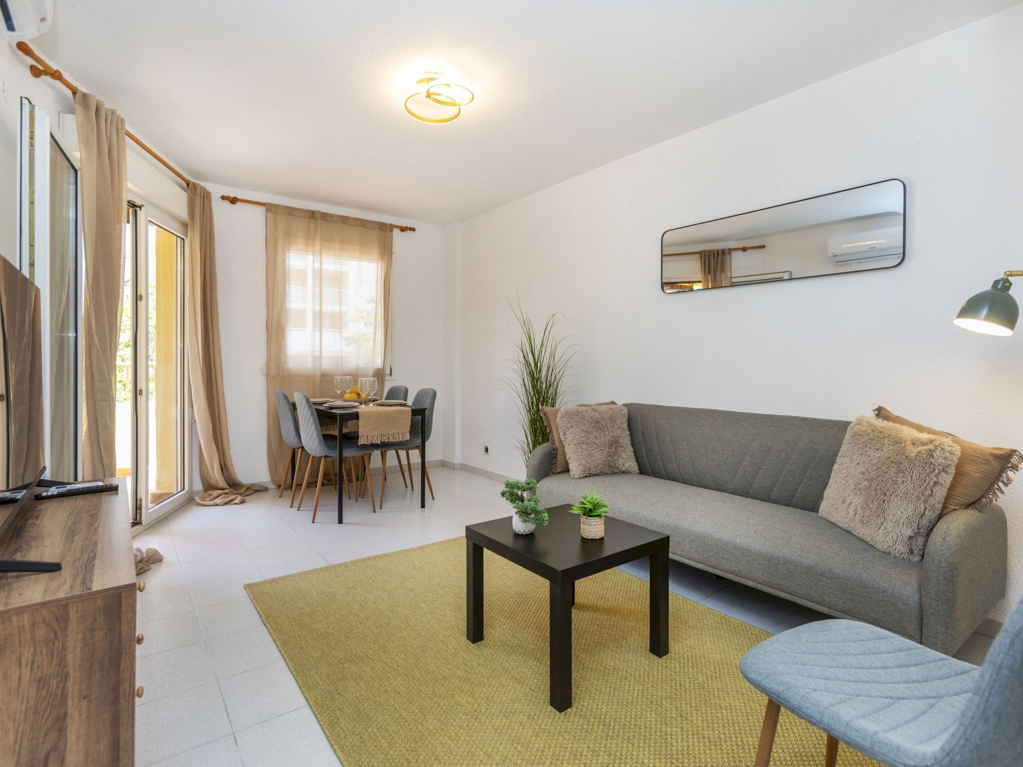 A modern living room with a sofa, a coffee table, and a dining area with a table and chairs.