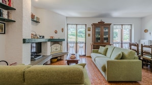 Una sala de estar acogedora con chimenea, sofá verde y un mueble de madera.