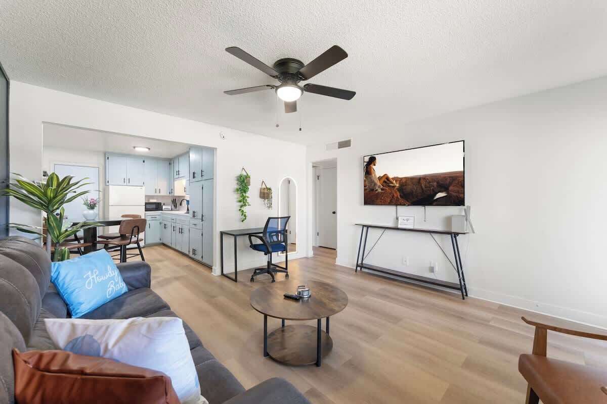 Uma sala de estar moderna com sofá, mesa de centro e ventilador de teto.