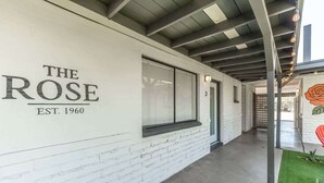 A corridor with a white brick wall, a sign reading 'THE ROSE EST. 1960', and a door marked with the number '3'.