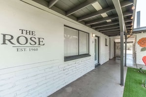 A corridor with a white brick wall, a sign reading 'THE ROSE EST. 1960', and a door marked with the number '3'.