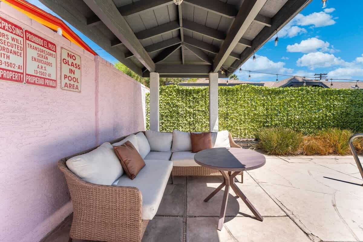 An outdoor patio with a covered seating area, a table, and a wall with a warning sign.