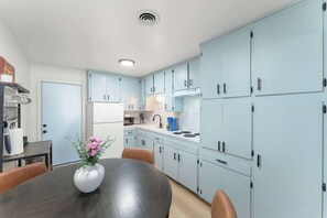 A modern kitchen with light blue cabinets, a central island, and a dining area with a vase of flowers. - The Rose #3|Pool|Gazebo|CentralPhx|Sleeps4 (Phoenix)