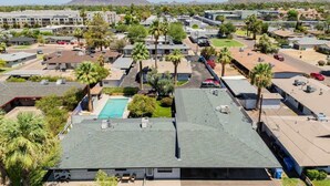 A residential area with multiple buildings, a swimming pool, and palm trees.