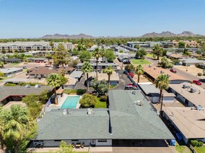 A residential area with multiple buildings, a swimming pool, and palm trees.