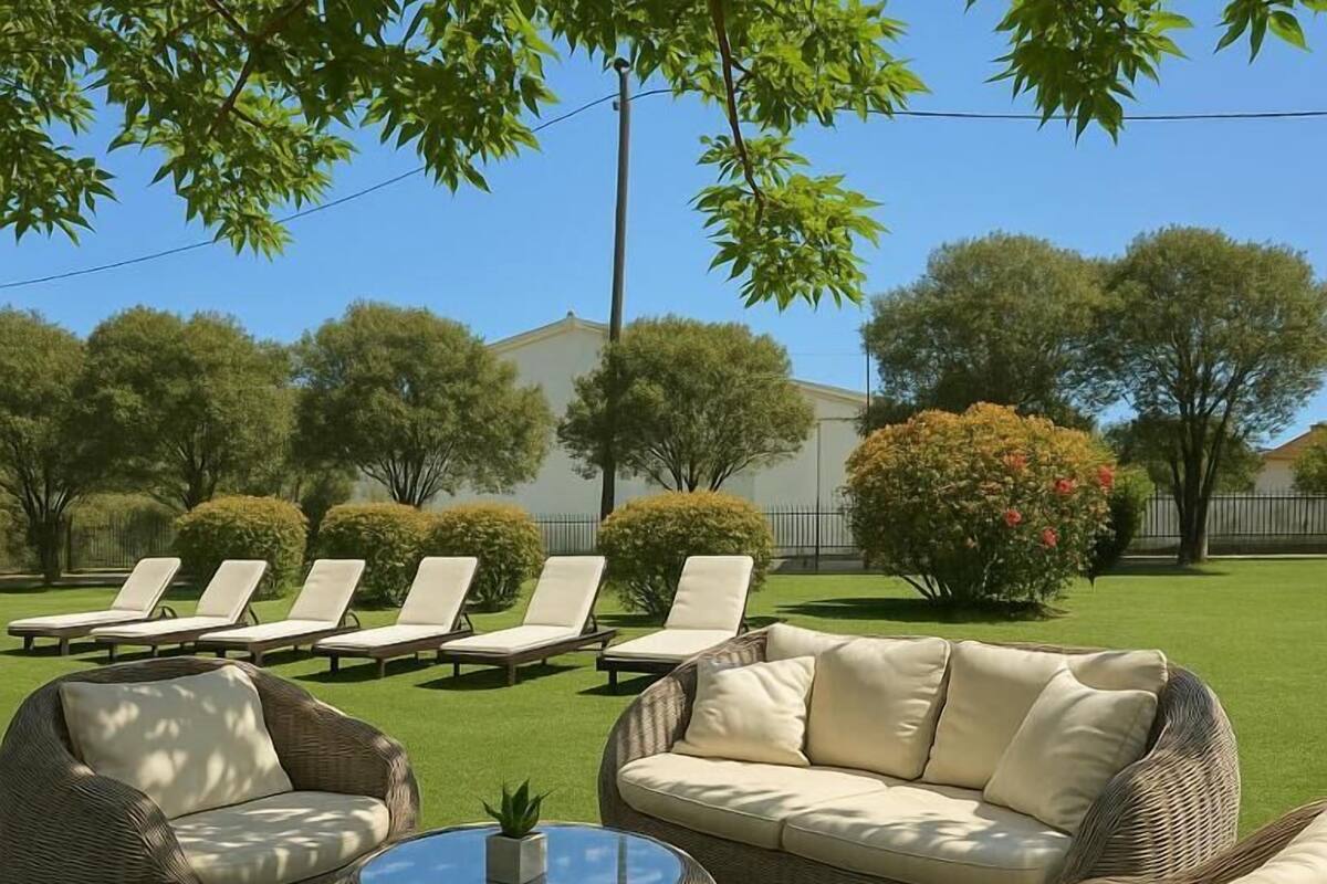 A patio with wicker furniture, including a sofa and chairs, and a round table.