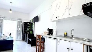 A modern kitchen with white marble cabinets, a built-in oven, and a bar area with a sink. - Marina Studio (Corfu)