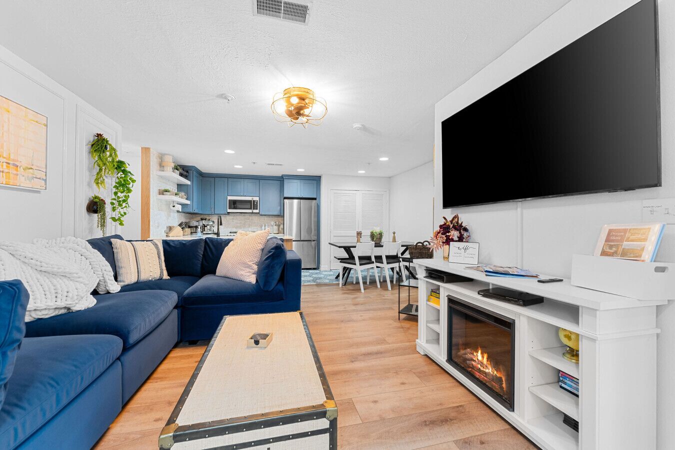 A modern living room with a blue sofa, a fireplace, and a flat-screen TV.