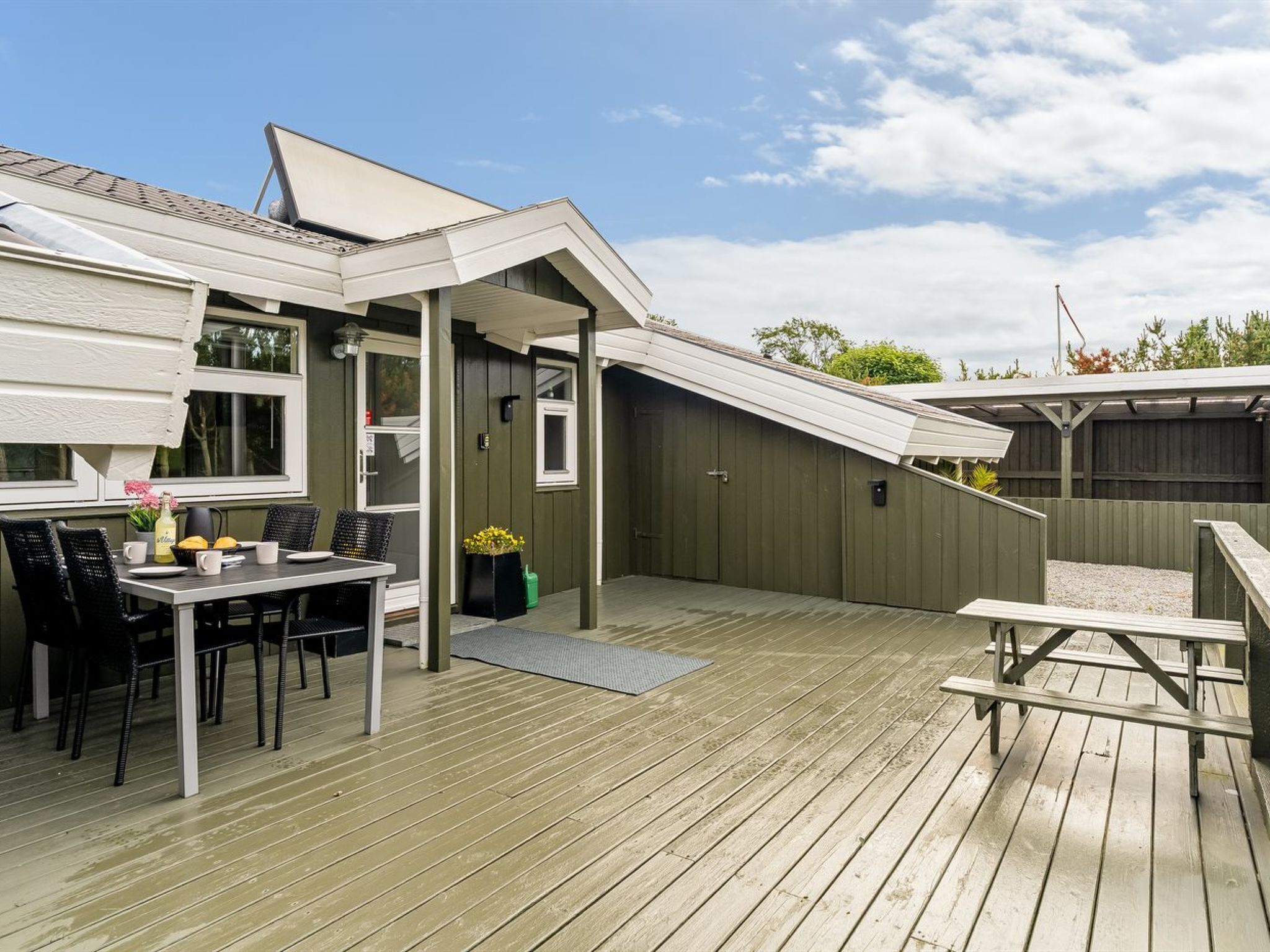 Une terrasse en bois avec une table et des chaises, un patio couvert et un garage.