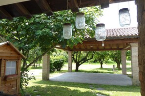 A wooden pergola with hanging mason jars and a wooden structure with a window.