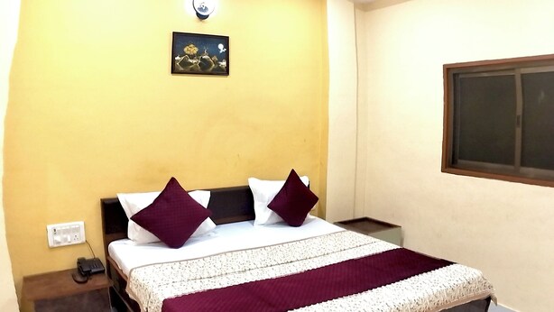 Une chambre d’hôtel équipée d’un lit, d’une table de chevet et d’un luminaire fixé au mur.